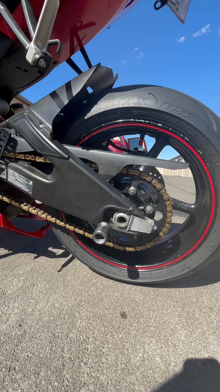 Red sport bike swingarm, chain and rear wheel after a full detail